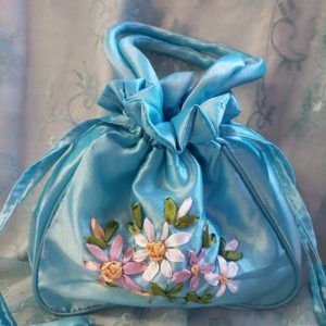 Kaunis kiiltävä Laukku koristekukilla, nyörikiinnityksellä ja sangoilla, turkoosi